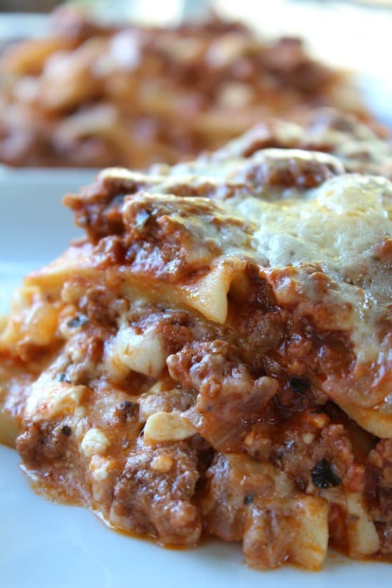 This Classic Lasagna is loaded with gobs of cheese and is a delicious family favorite lasagna recipe. Another view of a serving of lasagna on a white plate.