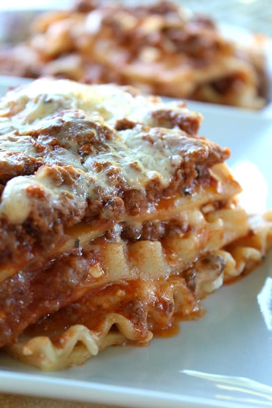 A close up photo of a serving of classic lasagna on a white plate.