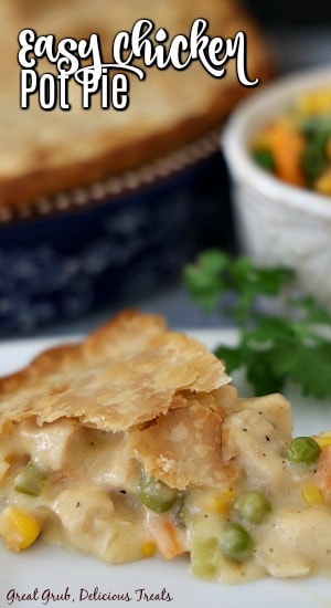 Easy Chicken Pot Pie is a quick and easy dinner recipe that is perfect for any night of the week. A slice of chicken pot pie on a white plate, garnished with parsely with a blue pie pan filled with pot pie in the background next to a small white bowl filled with mixed veggies.