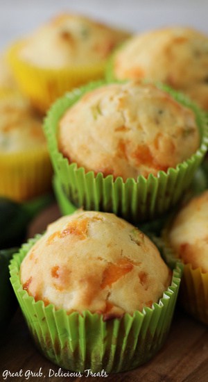 Jalapeño Cheese Muffins are an easy muffin recipe that is loaded with fresh diced jalapenos and sharp cheddar cheese. Jalapeno Cheese Muffins in green and yellow muffin liners stacked on top of each other.