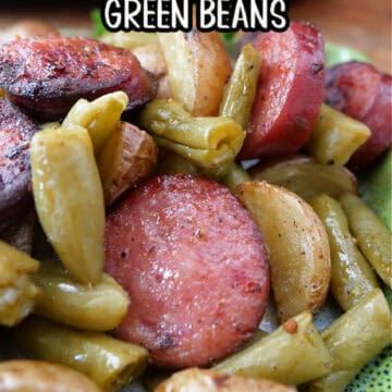A green plate with sliced smoked sausage, potatoes, and green beans with the title of the recipe in text at the top.
