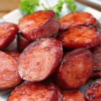 A white plate with a serving of sliced smoked sausage.