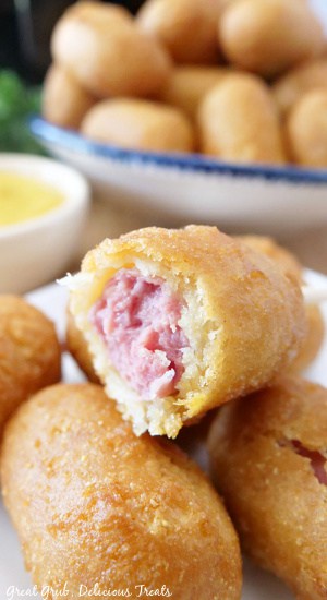 Mini Corn Dogs in Air Fryer are super easy to make and are the best appetizers for all occasions. A plate of corn dogs with one bite taken out of one.