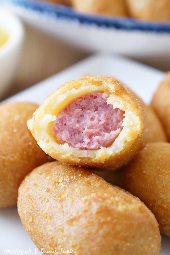 Mini Corn Dogs in Air Fryer makes a great snack, lunch, or dinner that is super kid friendly. mini corn dogs stacked up with a bite taken out of it.