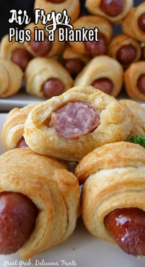 Pigs in a Blanket Air Fryer Recipe are incredibly easy to make and are a delicious appetizer or snack that everyone loves. Pigs in a blanket stacked up on a plate with a large plate in the background filled with crescent rolls.