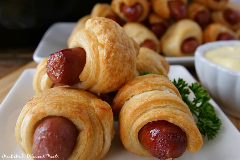 Pigs in a Blanket Air Fryer Recipe are quick, easy, and extra golden crescent rolls wrapped around little smokies. Five crescent rolls stacked up on a white plate.