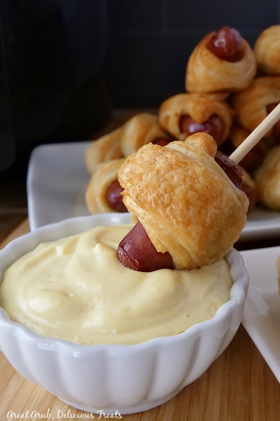 Pigs in a Blanket Air Fryer Recipe are crispy and delicious pigs in a blanket that can be quickly cooked in the air fryer. A pig in a blanket being dipped into dipping sauce.