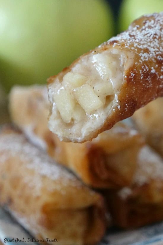 Apple Cream Cheese Egg Rolls are a delicious, crispy, apple and cream cheese filled egg roll, topped with powdered sugar. An apple egg roll with a bite taken out of it.