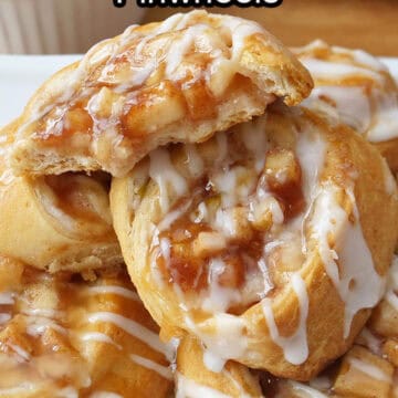 A white plate with a stack of apple cream cheese pinwheels, with one of them having a few bites taken out of it.