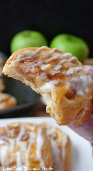 A close up of an apple cream cheese pinwheel being held up with a bite taken out of it.