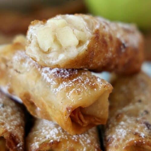 A stack of five apple egg rolls on a blue and white checkered plate.