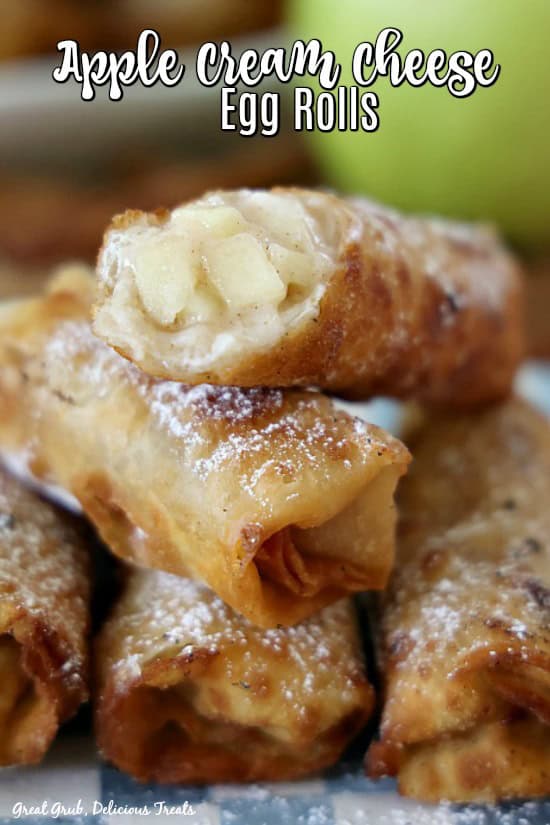 A stack of five apple egg rolls on a blue and white checkered plate.
