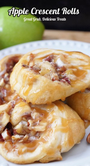 A round white plate with four apple crescent rolls on it.