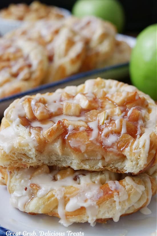 Two apple pastries stacked on top of each other and a bite taken out of the one on top.