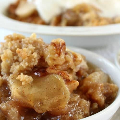 Two white bowls with servings of apple pear walnut crisp in them.