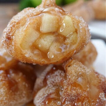 A small white plate with 4 apple pie bites on it with a bite taken out of one.