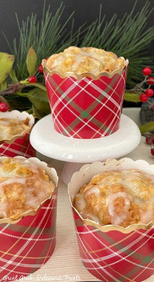 Apple Muffins with Glaze are soft and moist muffins that are loaded with diced Granny Smith apples and drizzled with a vanilla glaze. A muffin in a red plaid liner, topped with vanilla glaze.