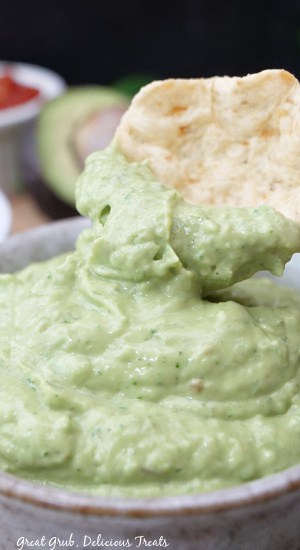 A close up of a tortilla chip that was dipped into the avocado dip.