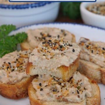 A white round plate with blue trim with slices of baguettes on it with bacon jam dip spread over them.