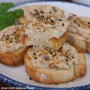 A round white plate with blue trim with slices of bacon jam dip covered baguettes.