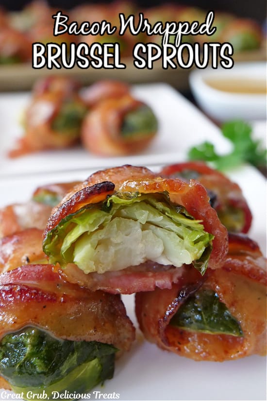 White plates with bite-size bacon wrapped brussel sprouts on them.