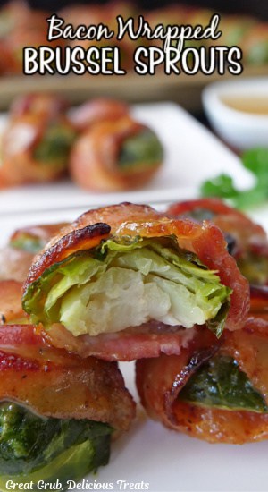A close up of a handful of brussel sprouts with bacon with a bite taken out of one of them.