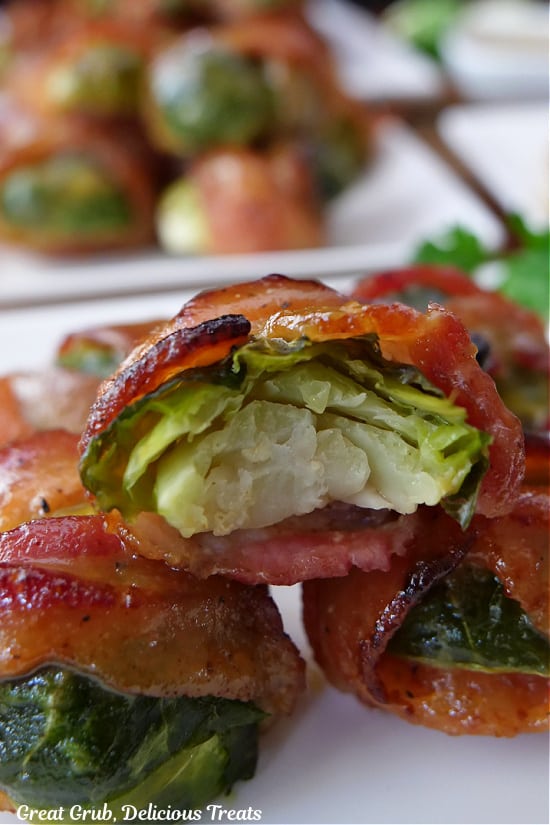 A close up of a bite taken out of a brussel sprout that is wrapped in bacon.