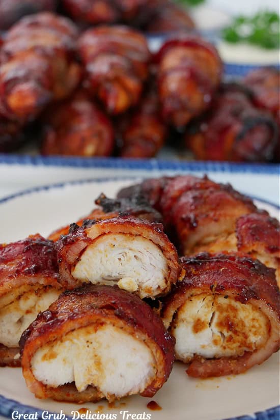 A white plate with blue trim with a few chicken strips on it that have been cut into bite size pieces with more strips in the background.