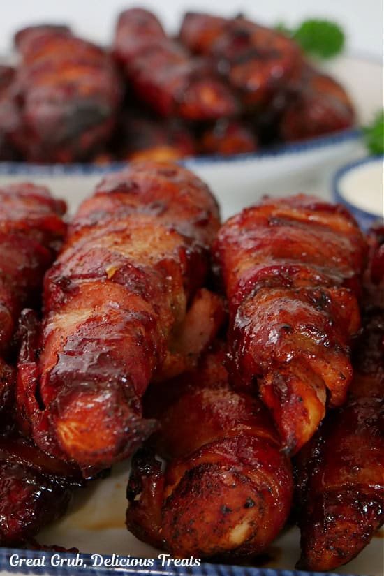 Smoked chicken strips stacked on each other on a white plate with blue trim.