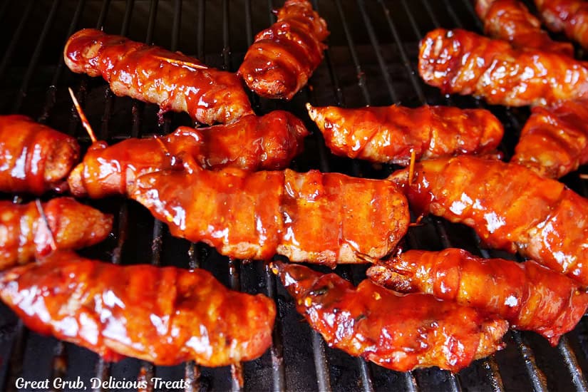 Bacon wrapped chicken strips on the smoker with additional BBQ sauce brushed on them.