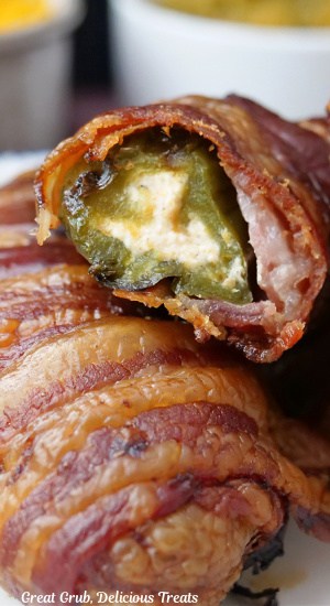 A close up of two jalapeno popper s with a bite taken out of one of them.