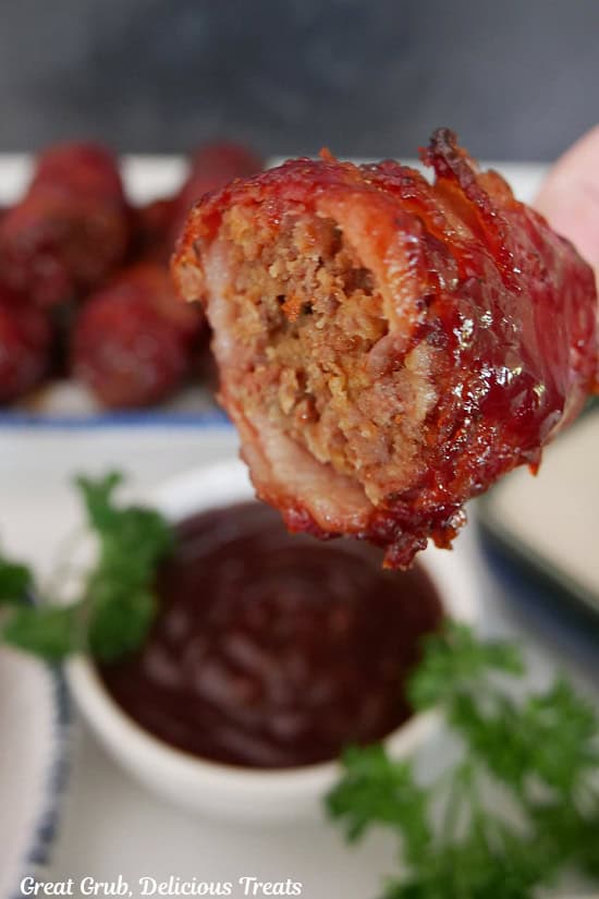 A mini bacon wrapped meatloaf with a bite taken out of it.
