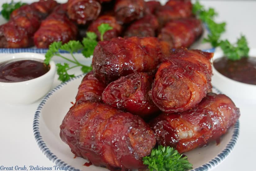 A white surface with tow white plates with blue trim filled with smoked bacon wrapped mini meatloaves on them.