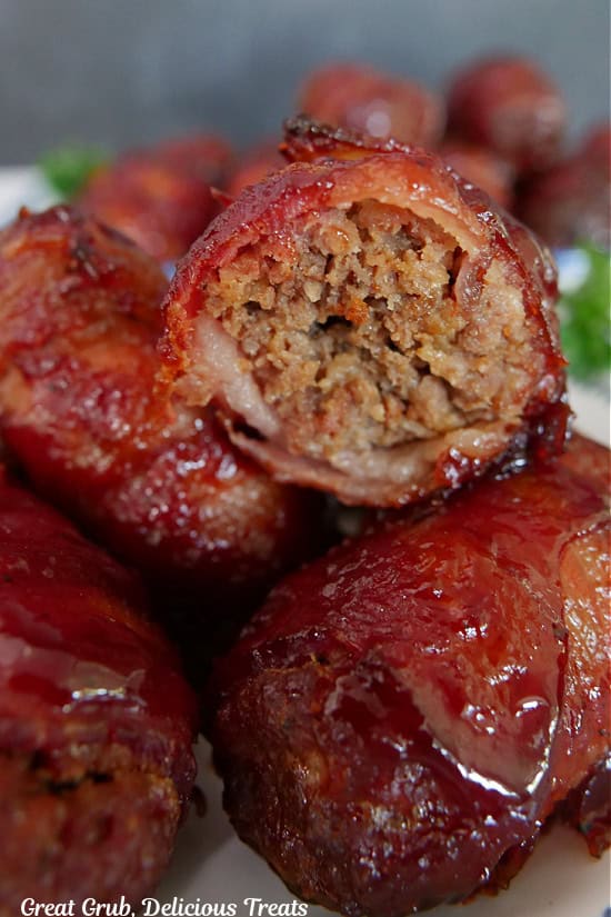 A stack of smoked bacon wrapped mini meatloaves with a bite taken out of the one on top.