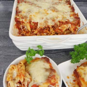 A white baking dish and two white plates with penne pasta in them.