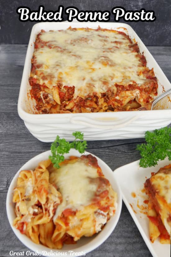 A white oblong baker and two  serving dishes filled with baked penne pasta.