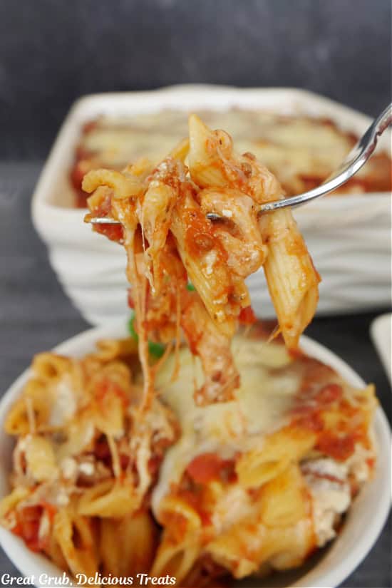 A cheesy bite of penne pasta on a fork.