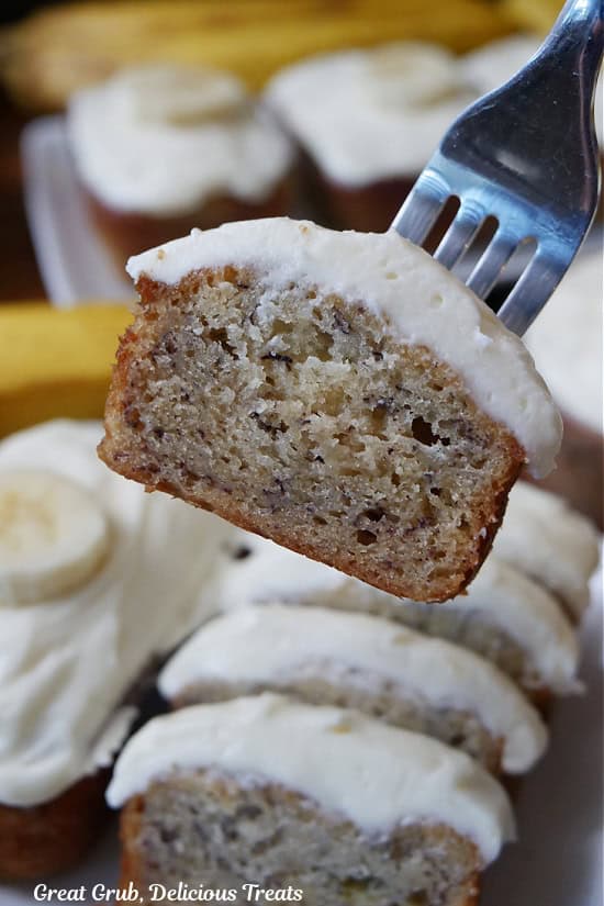 A bite of banana nut bread with frosting on a fork.