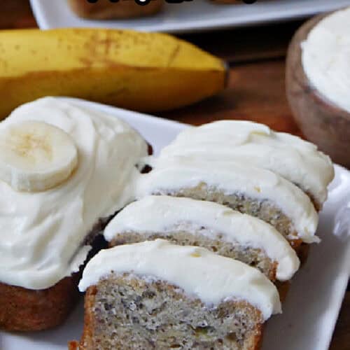 A white plate with two mini banana nut breads on it and one that has been sliced into bite-size pieces.