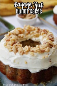 An individual banana bundt cake topped with cream cheese frosting and chopped walnuts.