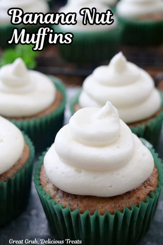Four banana muffins on a silver plate that have cream cheese frosting on top.