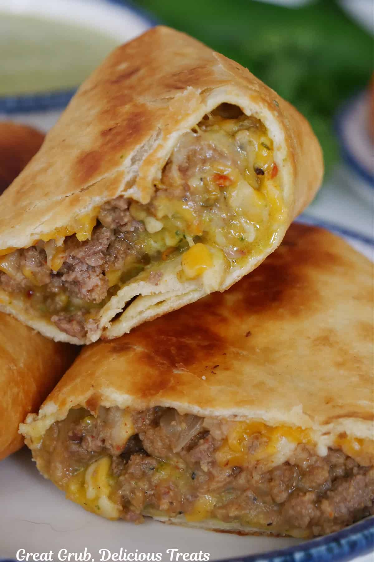Two fried beef and bean burritos cut in half on a white plate with blue trim.