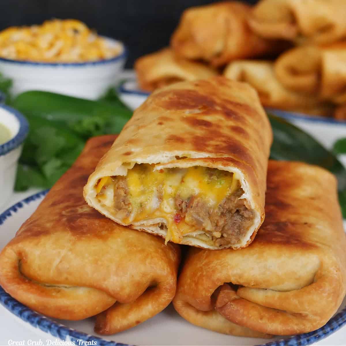Three fried burritos on a white plate with blue trim.
