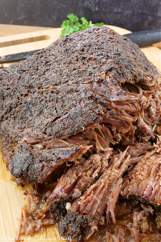 A close up of a brisket on a wood cutting board.