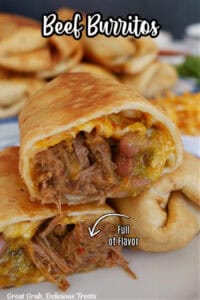 Two fried shredded beef burritos on a white plate with one of them cut in half and one half placed on the others, showing the inside ingredients.