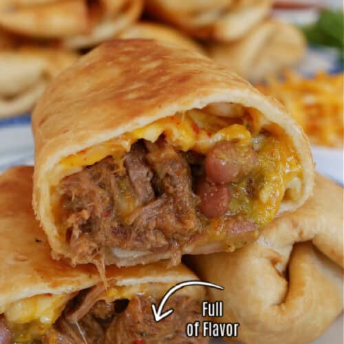Two fried shredded beef burritos on a white plate with one of them cut in half and one half placed on the others, showing the inside ingredients.