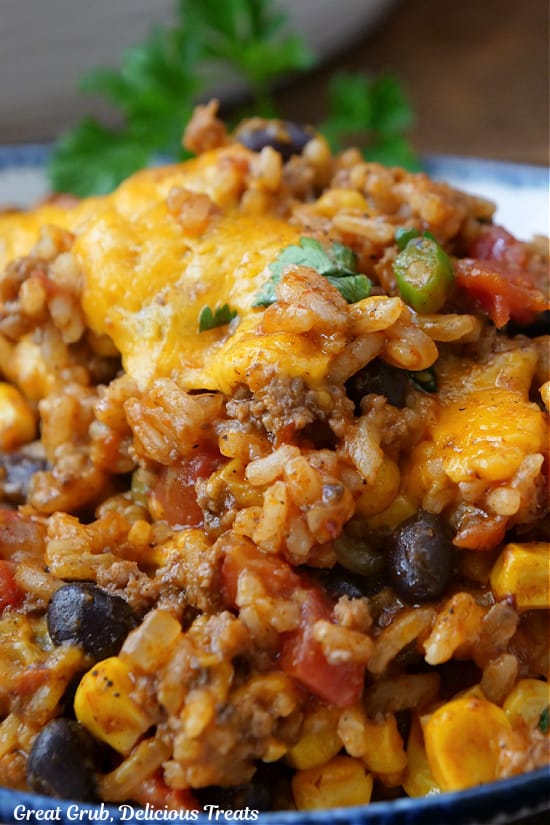 A close up of a bowl filled with rice, hamburger, beans, corn, and cheese.