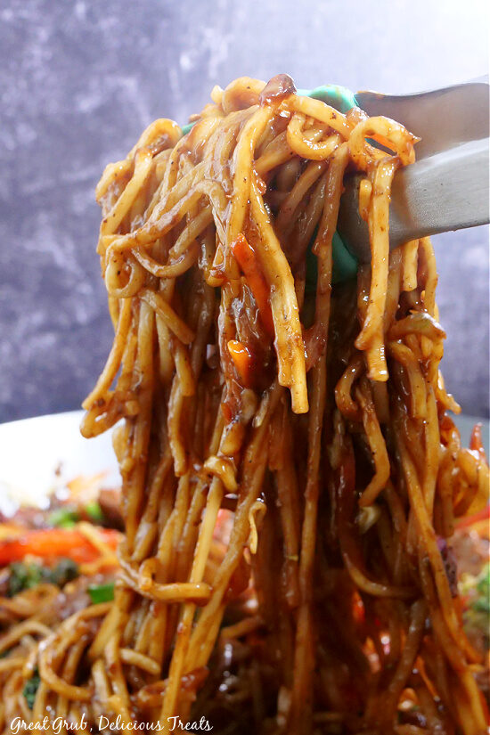 Beef Lo Mein is loaded with beef, snow peas, broccoli, red bell peppers, carrots, and a delicious homemade sauce. Noodles coated in a homemade sauce that is lifted up with tongs.