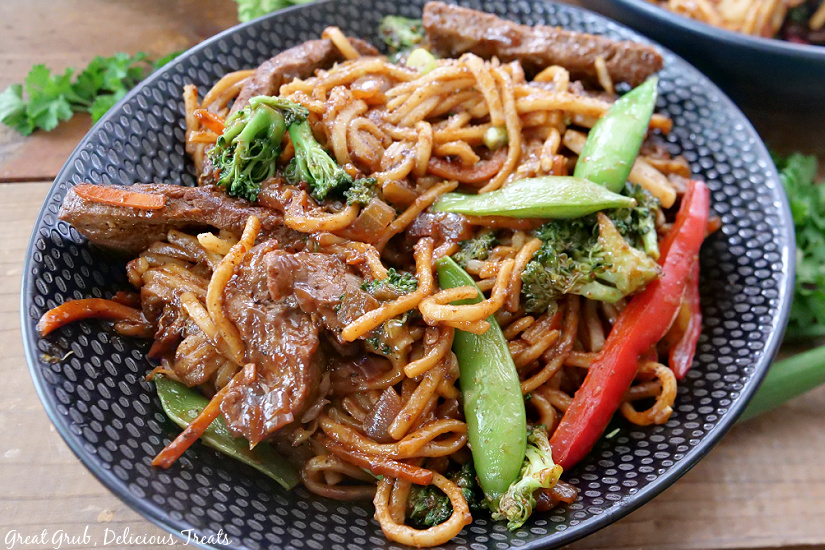 Beef Lo Mein is a delicious lo mein recipe that is made with beef, a variety of vegetables, and coated in a delicious sauce. A black bowl with beef lo mein.