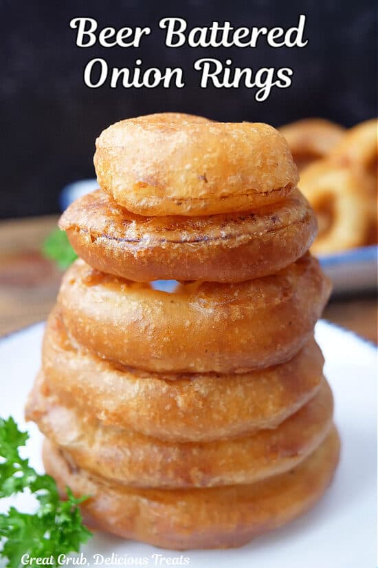 A stack of six onion rings on a white plate.